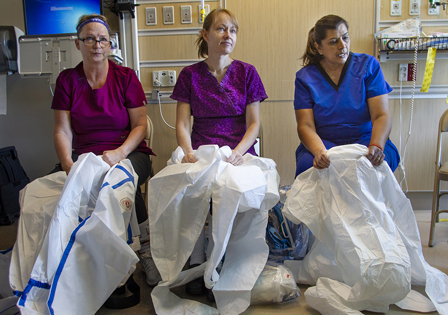 Kaiser Permanente South Sacramento Medical Center nurses Anna Mulessa, left, Katie McConniel, middle, and Pramila Ram, right, begin the laborious process of donning protective gear in preparation for an Ebola virus training in September at Kaiser Permanente Oakland Medical Center.