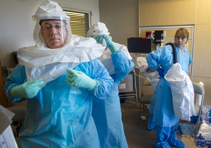 Gregory Smith, foreground, an emergency medicine physician at Kaiser Permanente South Sacramento Medical Center,  dons protective gear during the Ebola patient training at Kaiser Permanente Oaklannd Medical Center in September. In the background is Katie McConniel, RN.