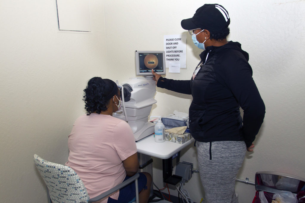 Mercedes Hyde, right, a licensed vocational nurse, shows Maisha Cole of Richmond an image of her retina at the COVID-19 and flu vaccine clinic in Richmond.