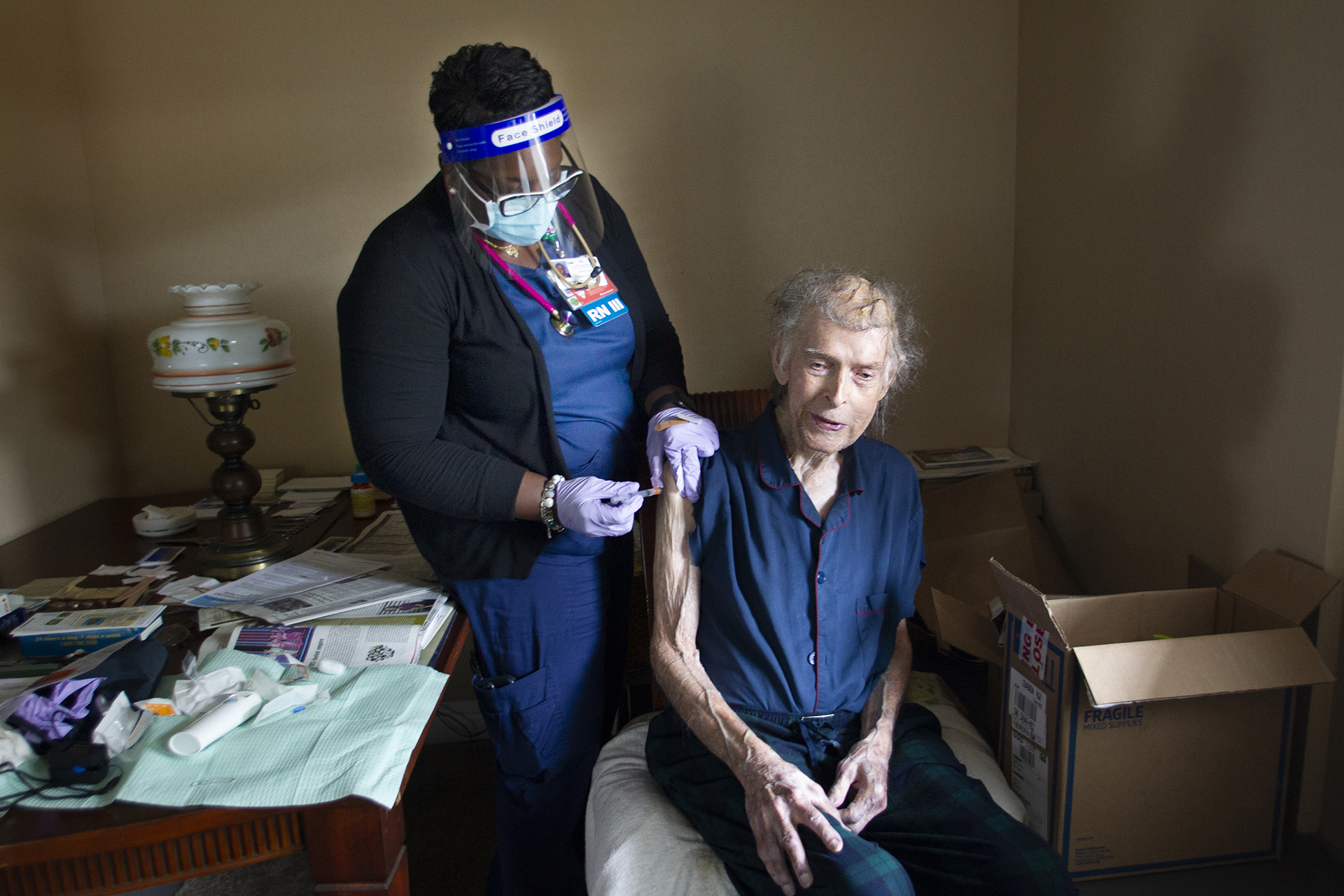Nurse giving a vaccination to a man in his home