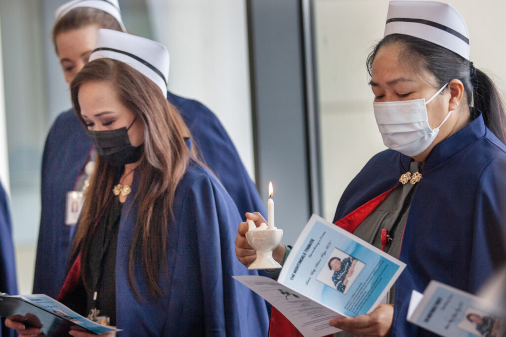 Sherie Domingo, RN, at right, holds a candle for Leticia Dicioco-Reyes, RN, who died on Dec. 20 after working 21 years at the Kaiser Permanente Redwood City Medical Center.